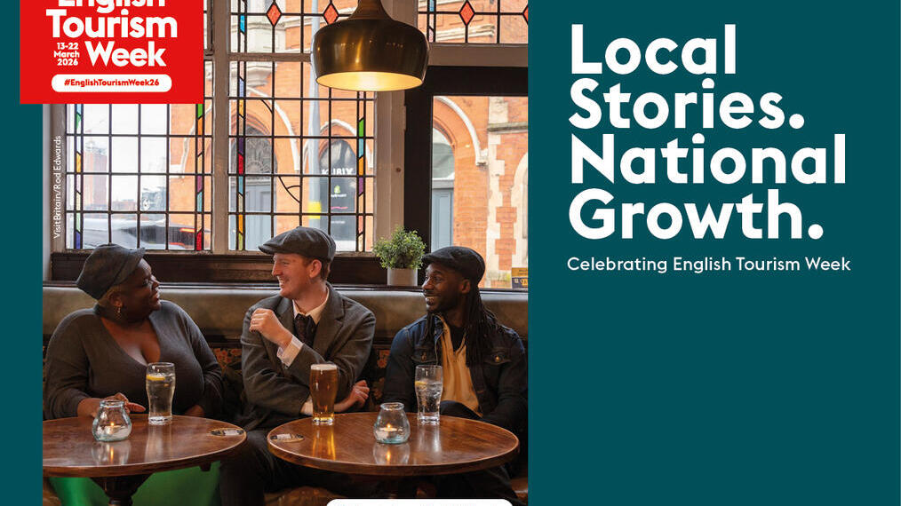Three people sit and chat in a pub in Birmingham, West Midlands, promoting English Tourism Week 2024. Stained glass window in background.