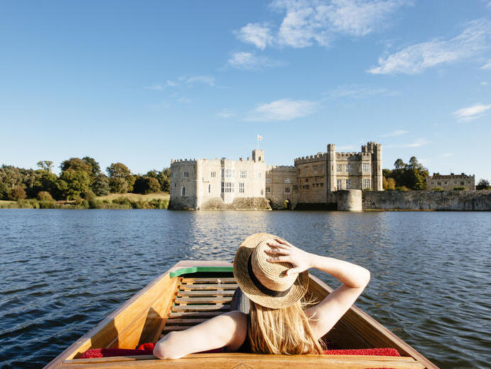Femme dans une barque sur les douves regardant vers le château