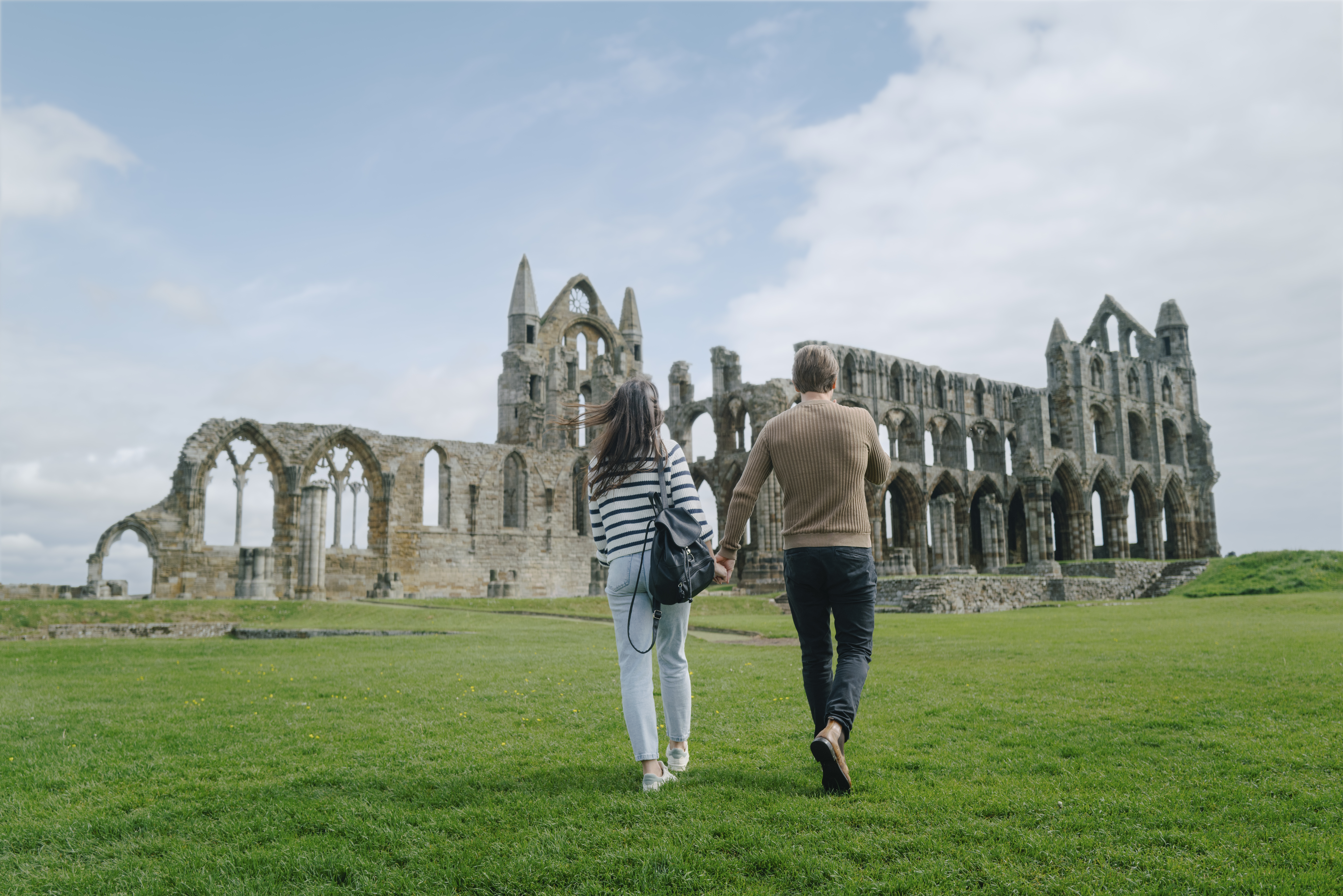 A man and woman walking towards a heritage Abbey building