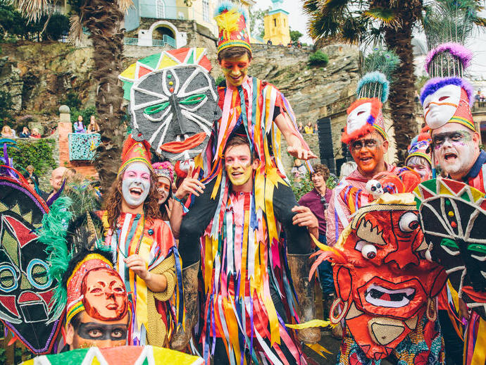 Gruppe von Darstellern in bunten Kostümen mit bemalten Gesichtern