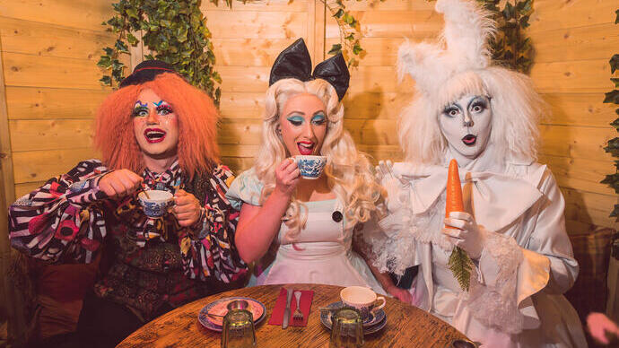 Three people dressed up in fancy dress at a tea party