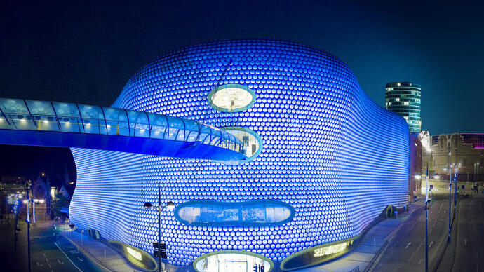Steel framework building lit up in a blue light at night