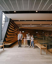 A man, a woman and two girls walking inside a modern museum.