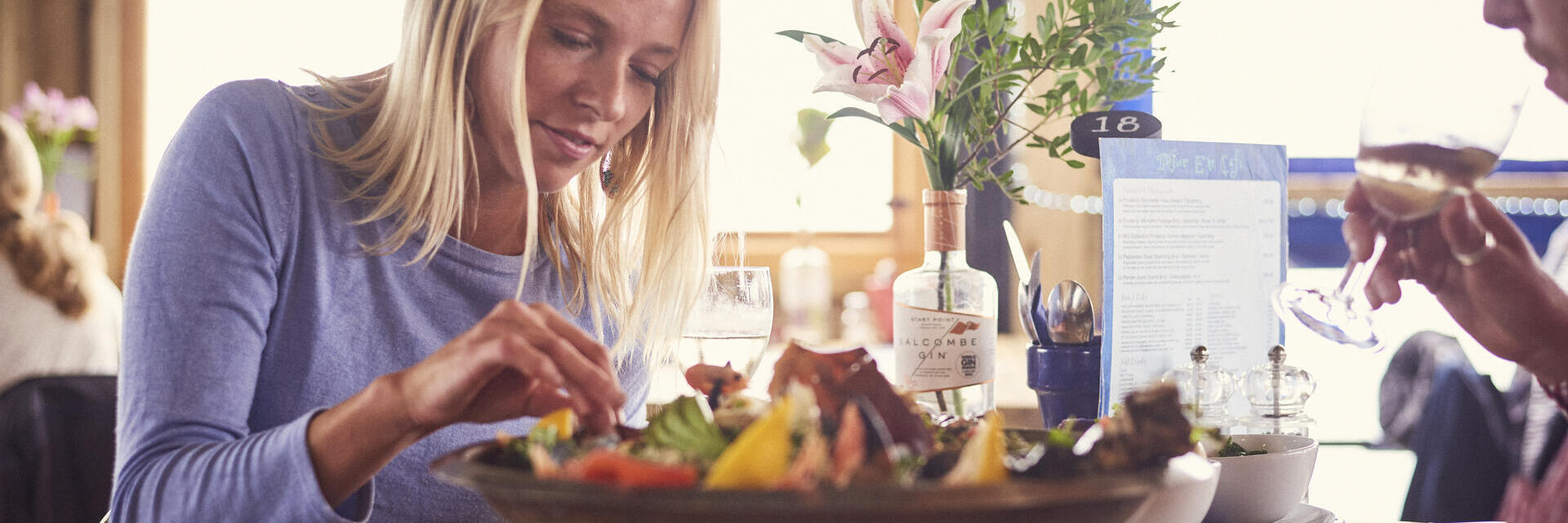 Mujer rubia y hombre sentados a la mesa, comiendo una bandeja de marisco