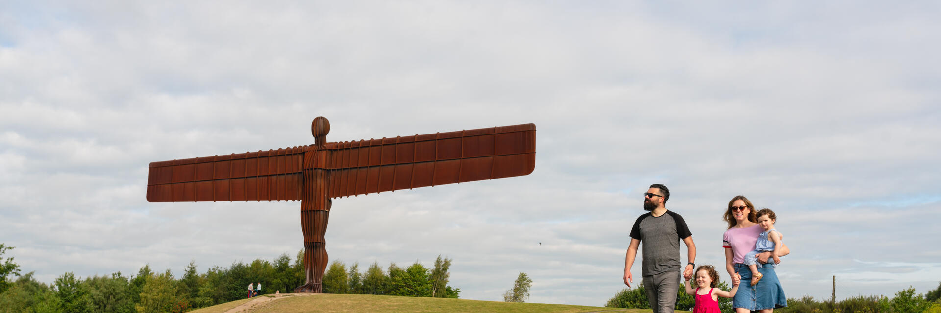 Eine Familie spaziert vor dem ikonischen Angel of the North, der sich südlich von Newcastle Gateshead befindet