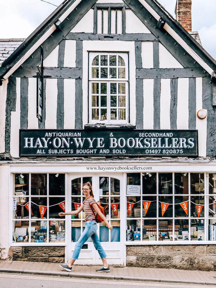 Young woman wearing backpack walks past bookshop