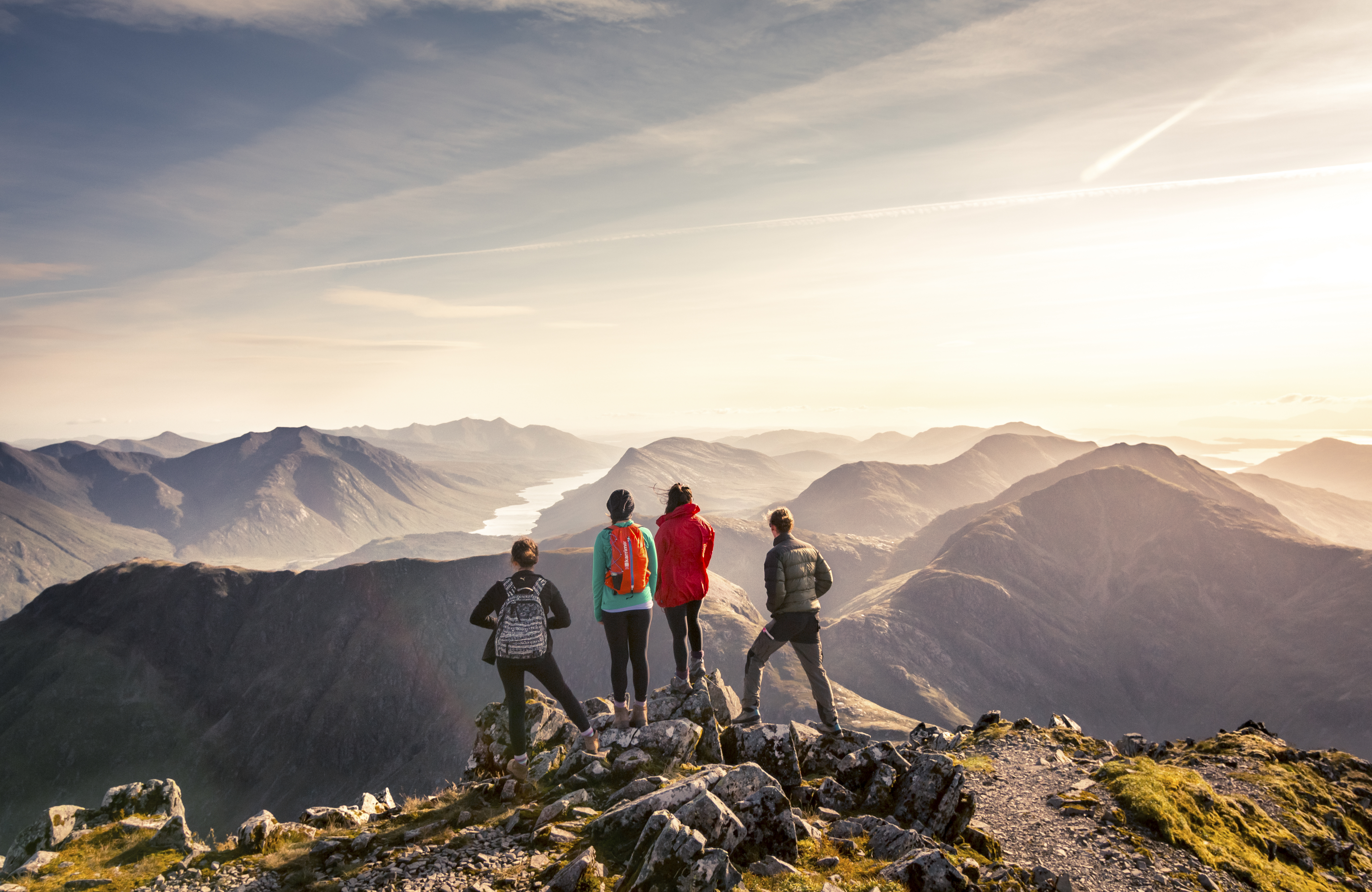 A group of people standing on high point looking at the mountain view below