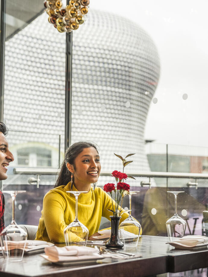 Three young people sat at a dining table with high views