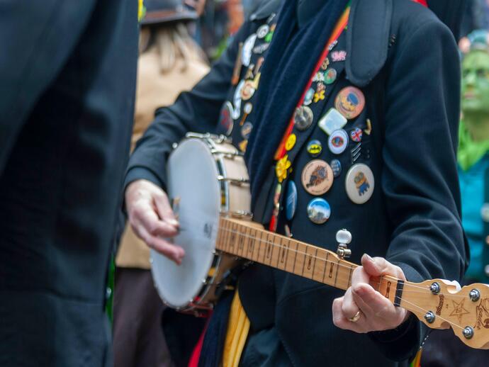 A folk player covered in badges at a music festival.