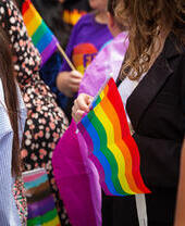 Crowds of people holding rainbow flags at a Pride Parade in London.