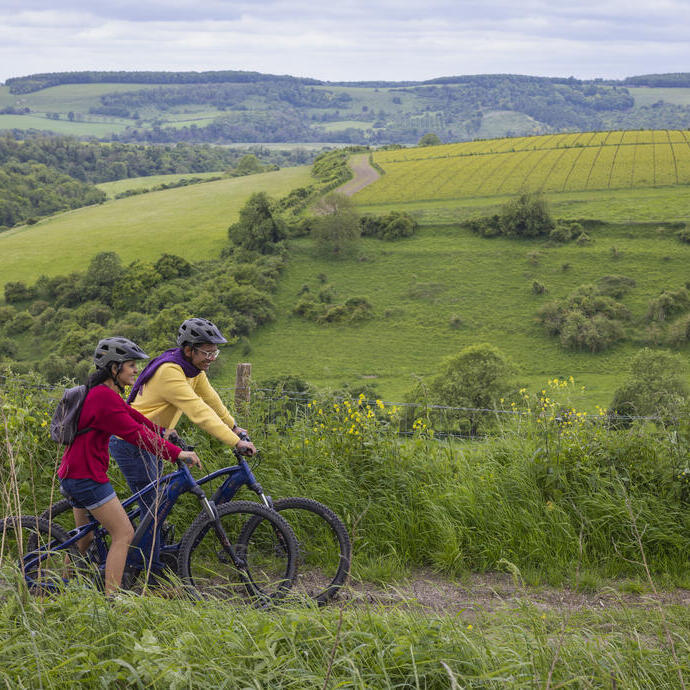 A man and a woman stand with bicycles wearing helmets