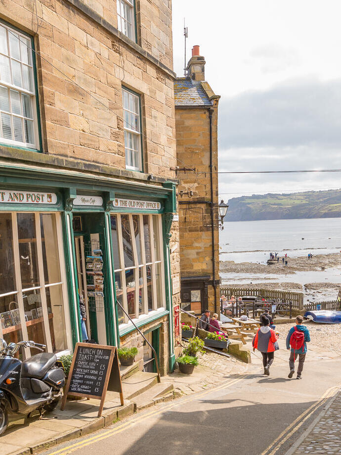 Couple walking down a narrow street with the sea in the distance