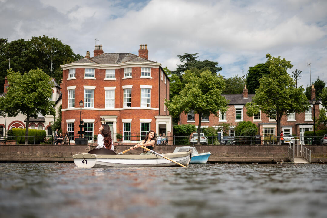 Two women sit in a row boat in a City