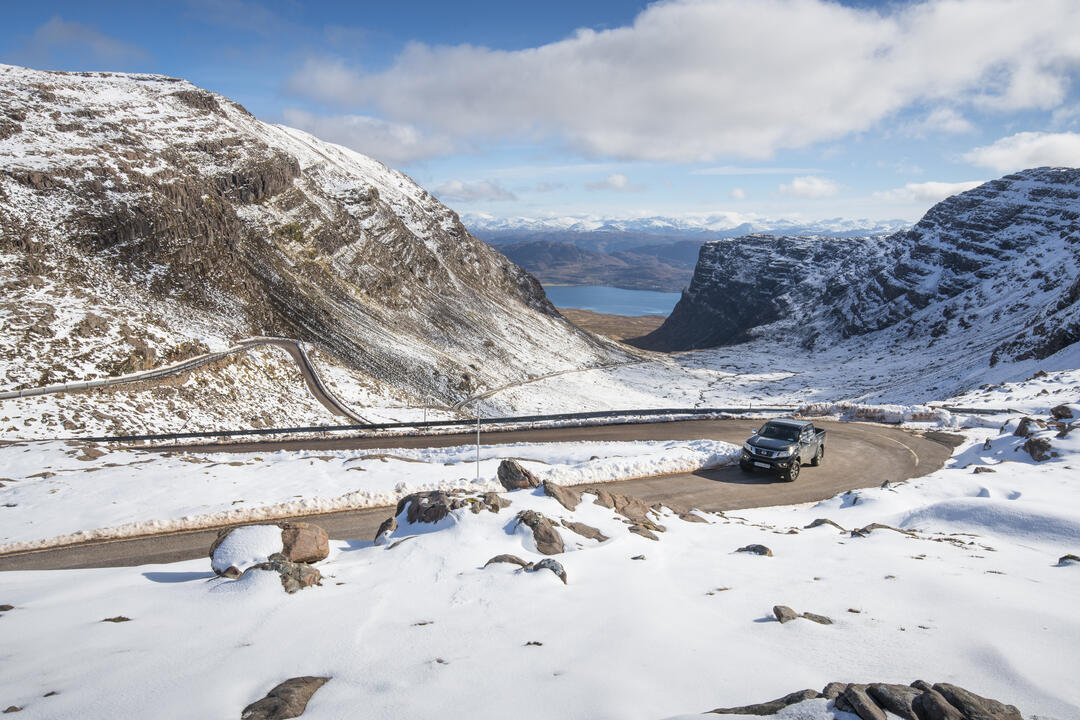 سيارة على طريق جبلي محاط بالثلوج