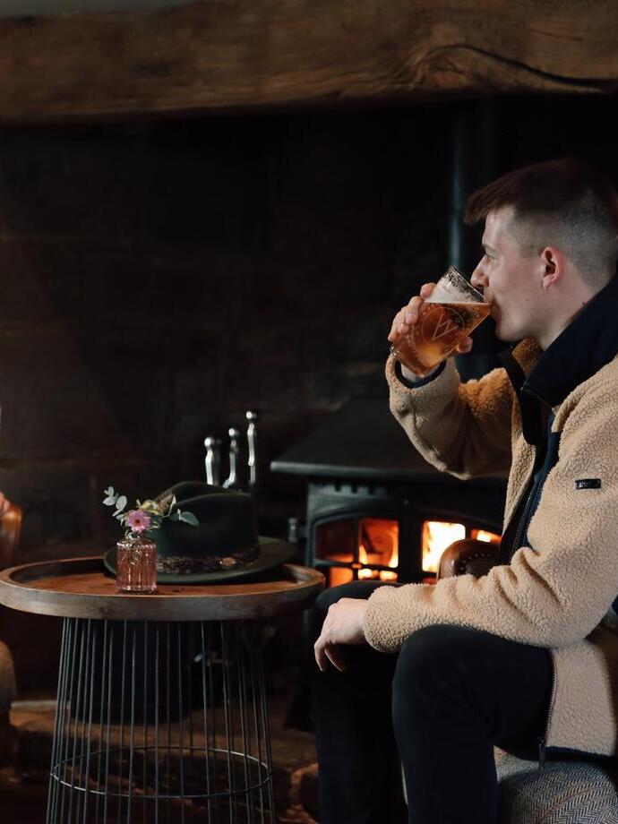 Man and woman having a drink by a log fire