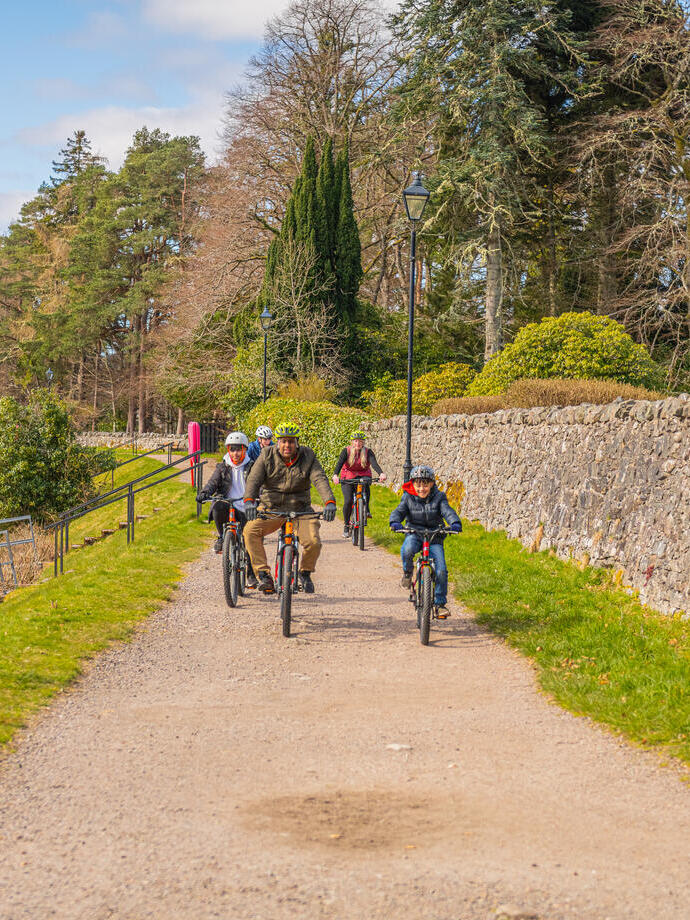 Une famille avec trois garçons fait du vélo le long d'un chemin de halage.