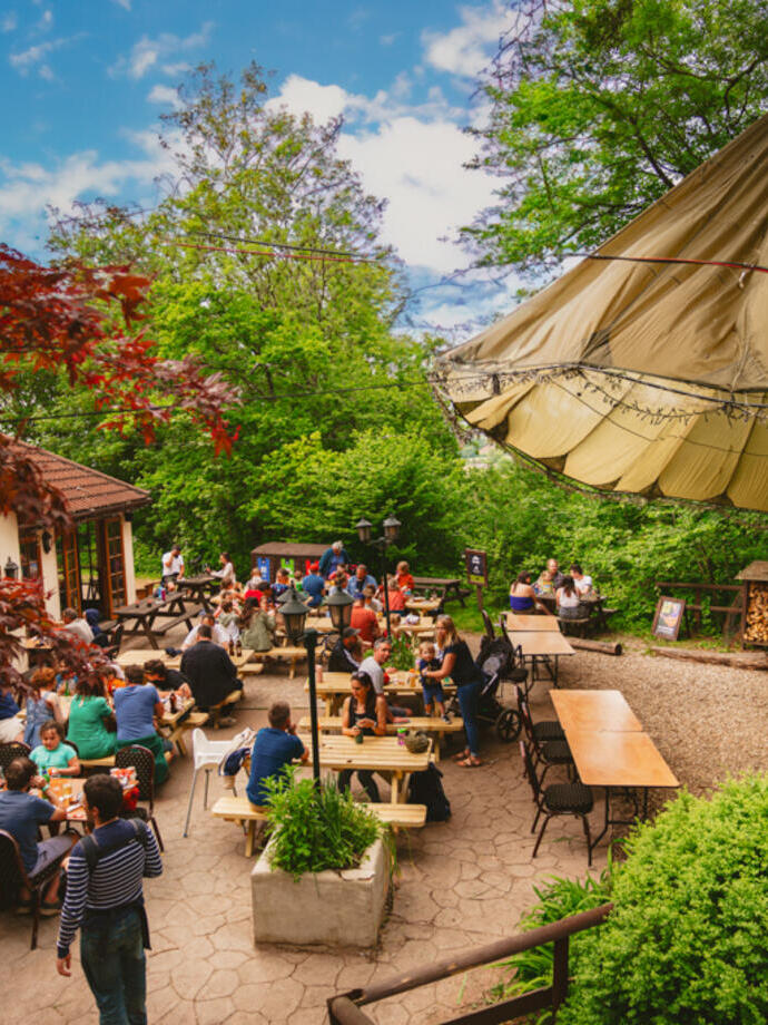 External dining area showing people sitting at wooden benches in a courtyard area at a family camp grounds.