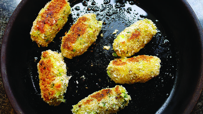 Mit Semmelbröseln panierte Würstchen, die in einer Pfanne gebraten werden