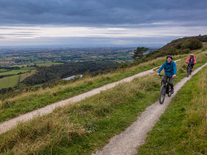 Hombre y mujer montando en bicicleta por un sendero en una cresta