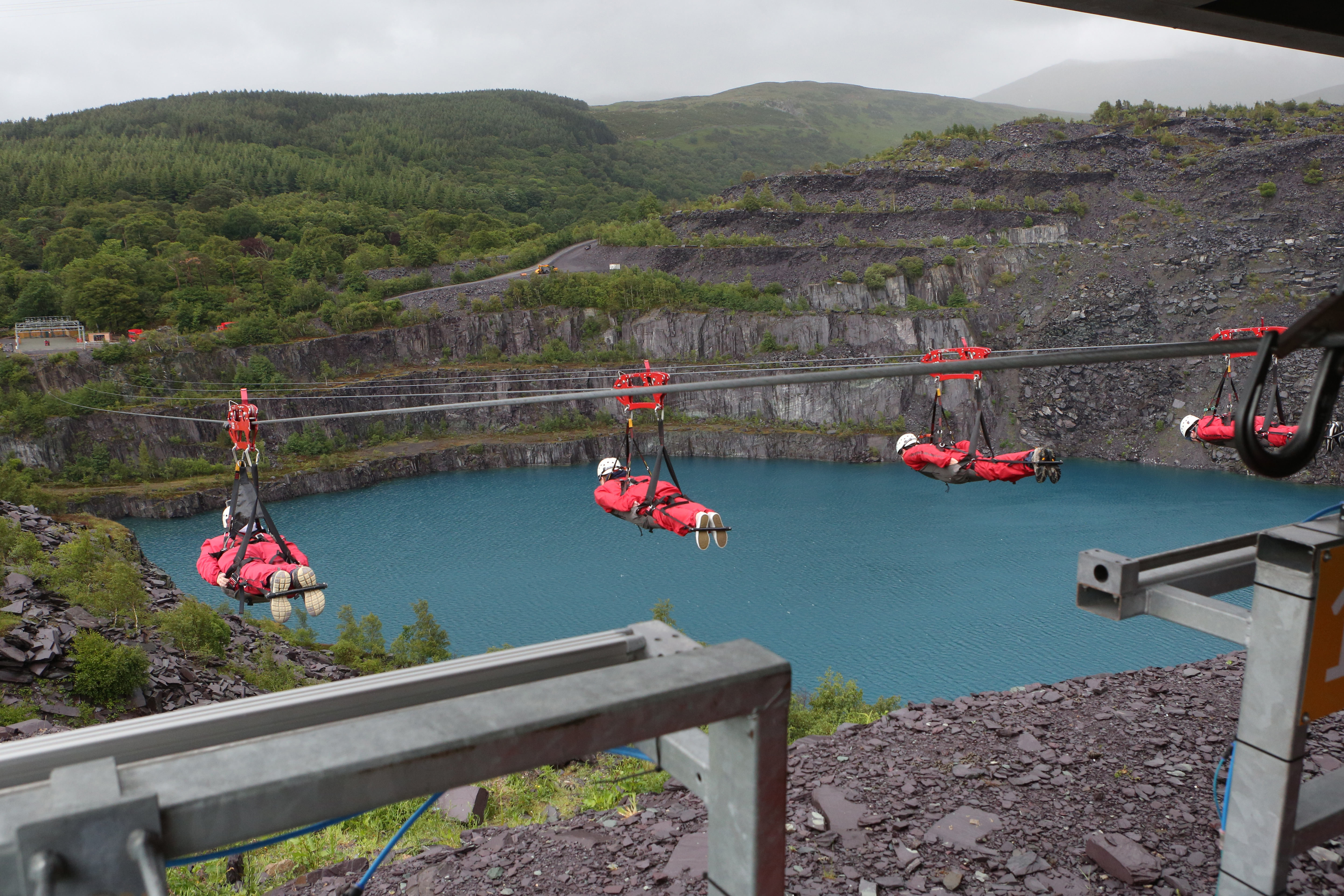 People ziplining across a large water filled quarry