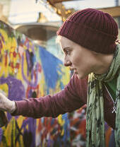 Mujer utilizando una lata de pintura en aerosol para crear un mural de arte callejero