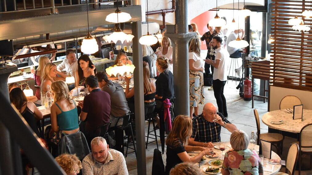 Des groupes de personnes assises à des tables à l'intérieur du Maray, un restaurant situé dans le quartier animé des docks de Liverpool