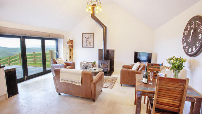 A living room with matching brown leather sofa and armchairs and a wood burner.