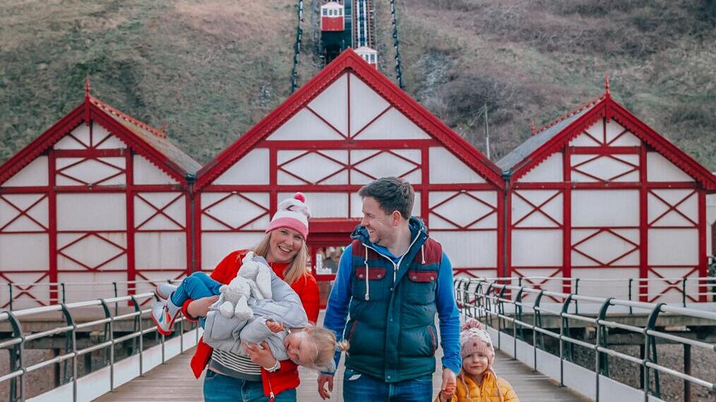 Family walking with a dog below a funicular cliff railway
