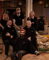 Staff posing on top of coffee bean sacks at Dear Green Coffee, Glasgow