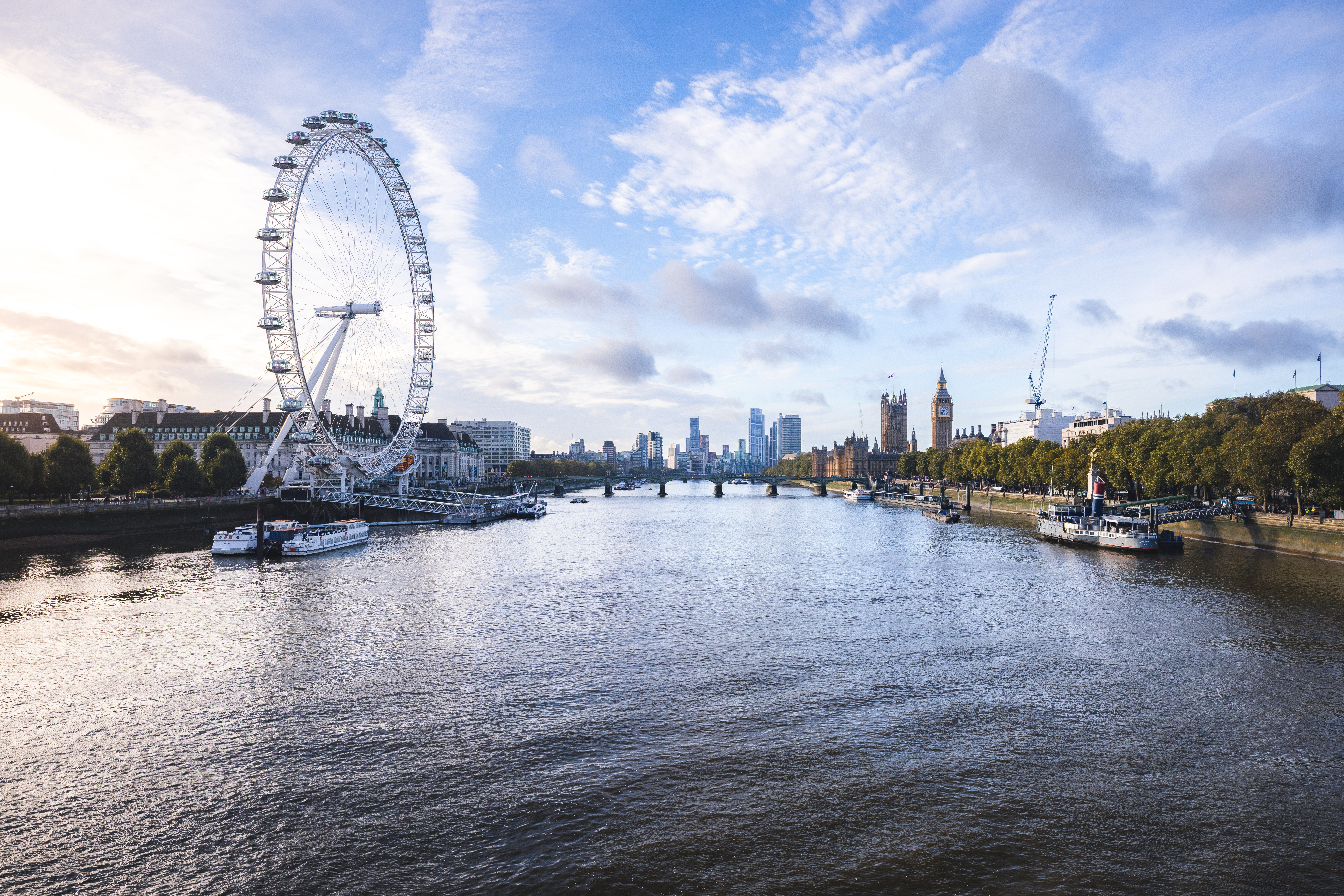 A river view to an observation wheel and a city skyline