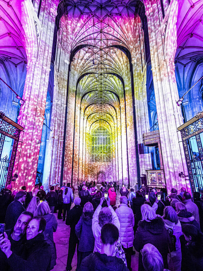 Group of people looking and photographing light show in a cathedral
