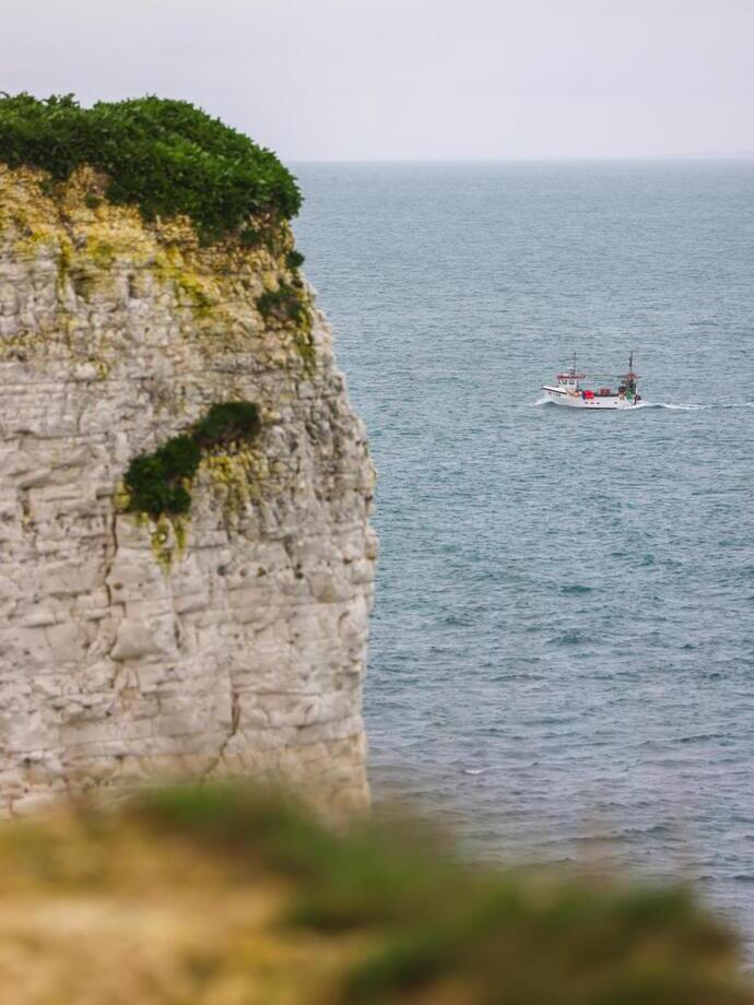 A fishing boat cruising past tall cliffs.