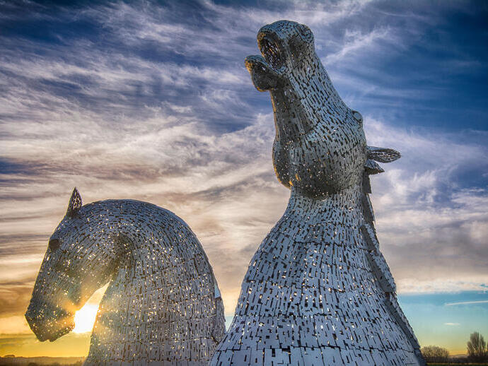 Pareja de enormes esculturas de cabezas de caballo al atardecer.