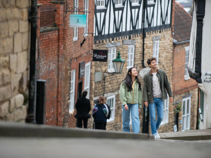 A woman and a man walk up a steep hill in a heritage City
