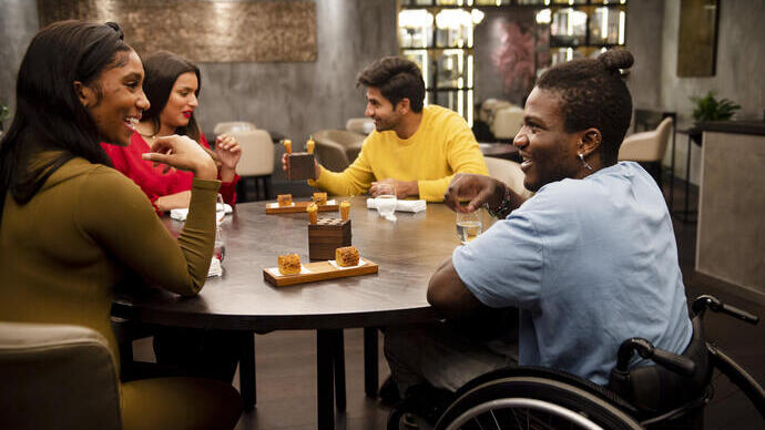 Group of friends, one in a wheelchair sitting at a table in a restaurant