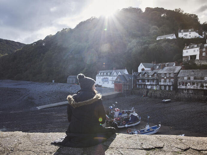 Woman sitting on harbour wall in the sunshine