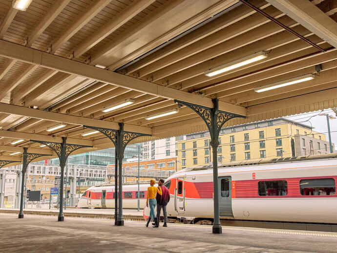 Man and woman walk along a train station platform