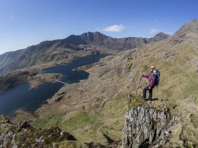 Woman standing on a rock, high above the lake in a valley