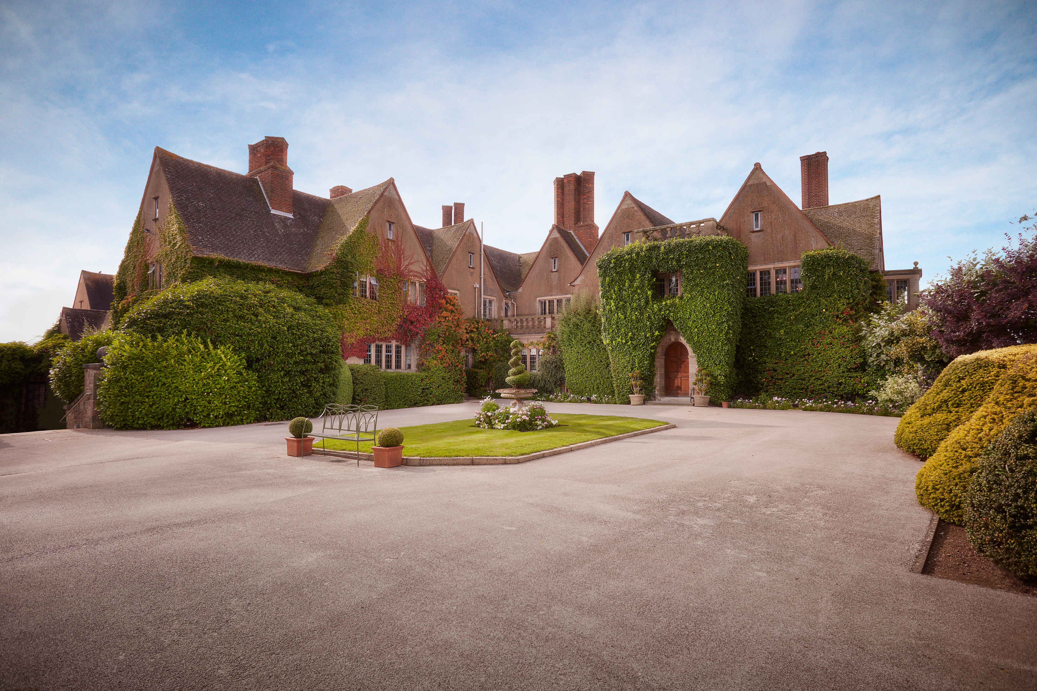 The front entrance, driveway and manicured gardens of a county hotel and spa.