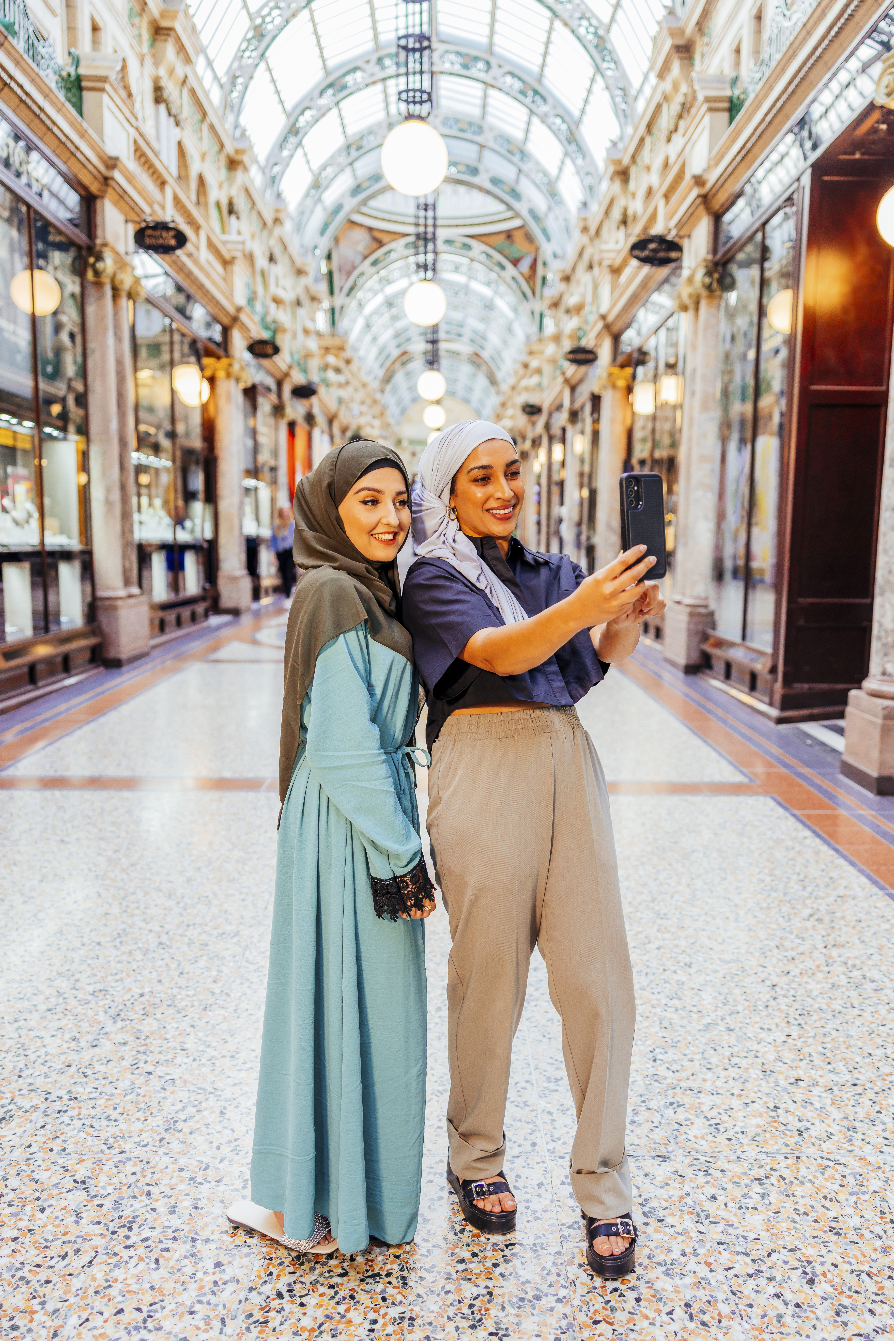 Two women take a picture together in an indoor shopping arcade