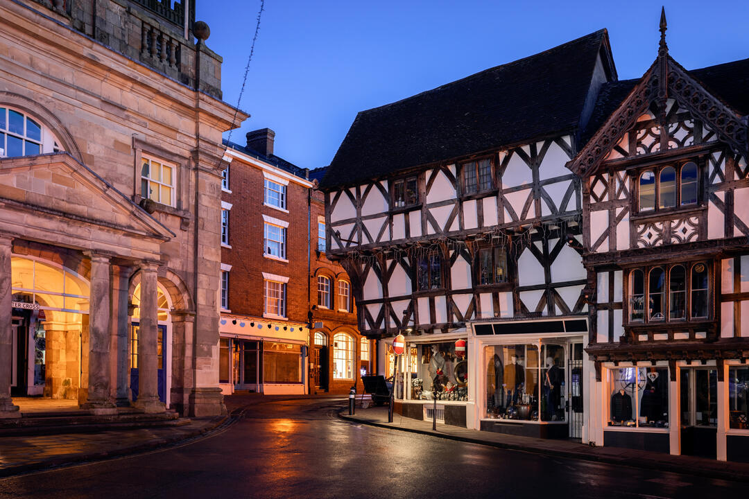 Black and white tudor building in a town centre at dusk