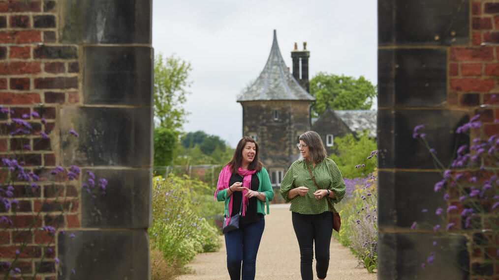 Two women walking toward archway, RHS Bridgewater