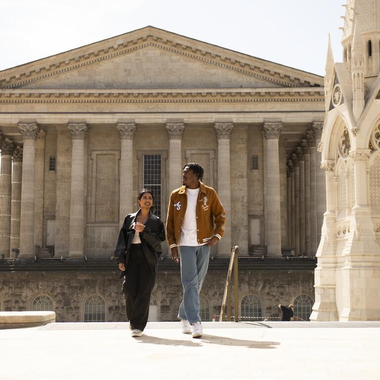 A couple strolling through an ornate English Town Square