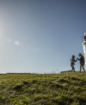 Due bambini che giocano in uno spazio aperto vicino a un faro