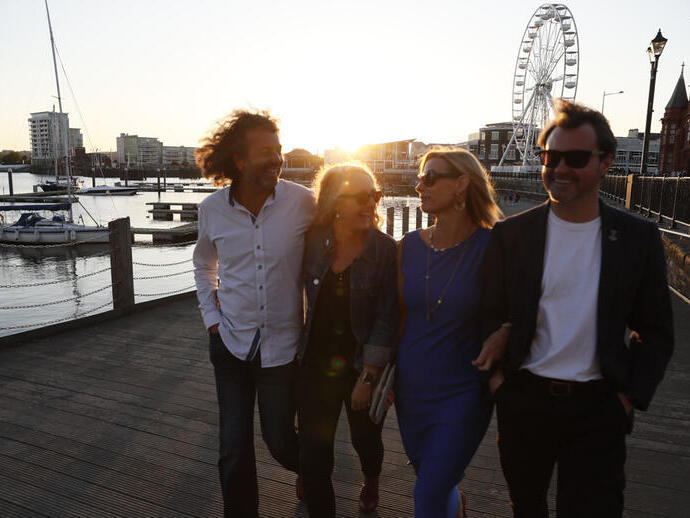 A group of people exploring the harbour of Cardiff at sunset