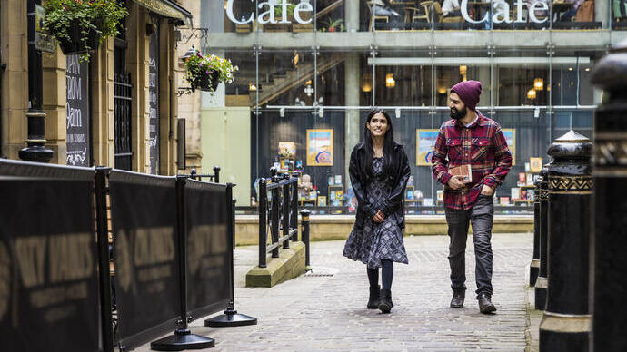 A woman and a man walk through a town centre