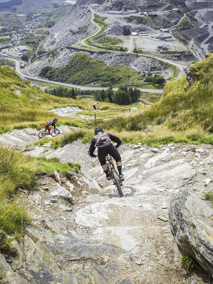 Menschen, die mit Mountainbikes einen steilen Hügel hinunterfahren.
