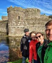Un grupo de personas posando junto al agua cerca del castillo de Beaumaris, en Gales