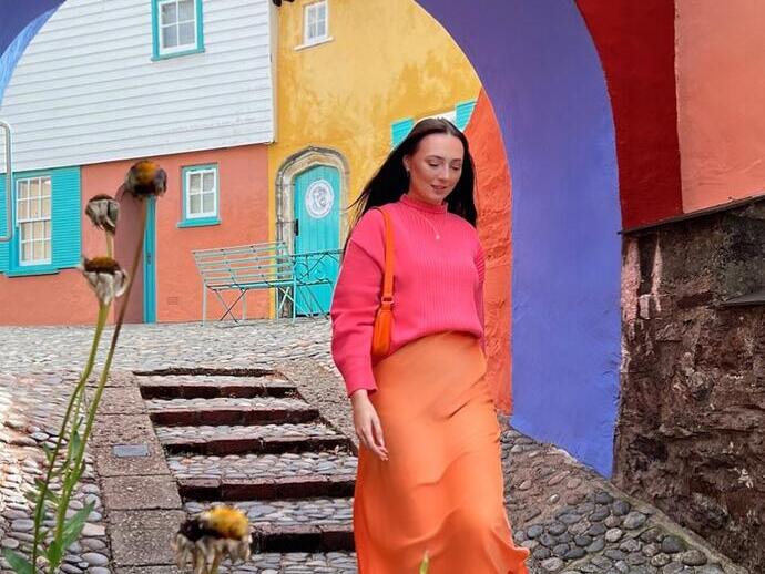 Femme marchant dans une rue pavée, sous une arche colorée