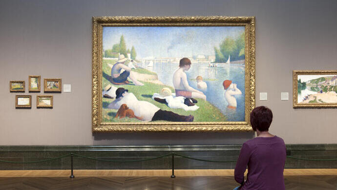A woman sitting in a gallery looking at a painting